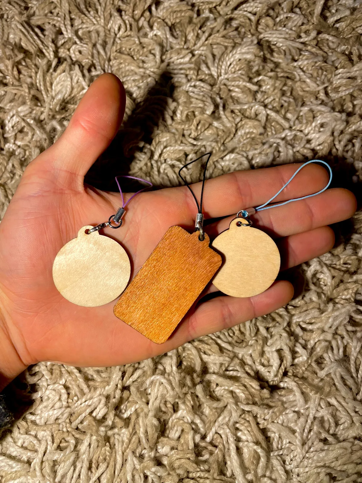 Tres llaveros de madera en formas de círculo, rectángulo y corazón